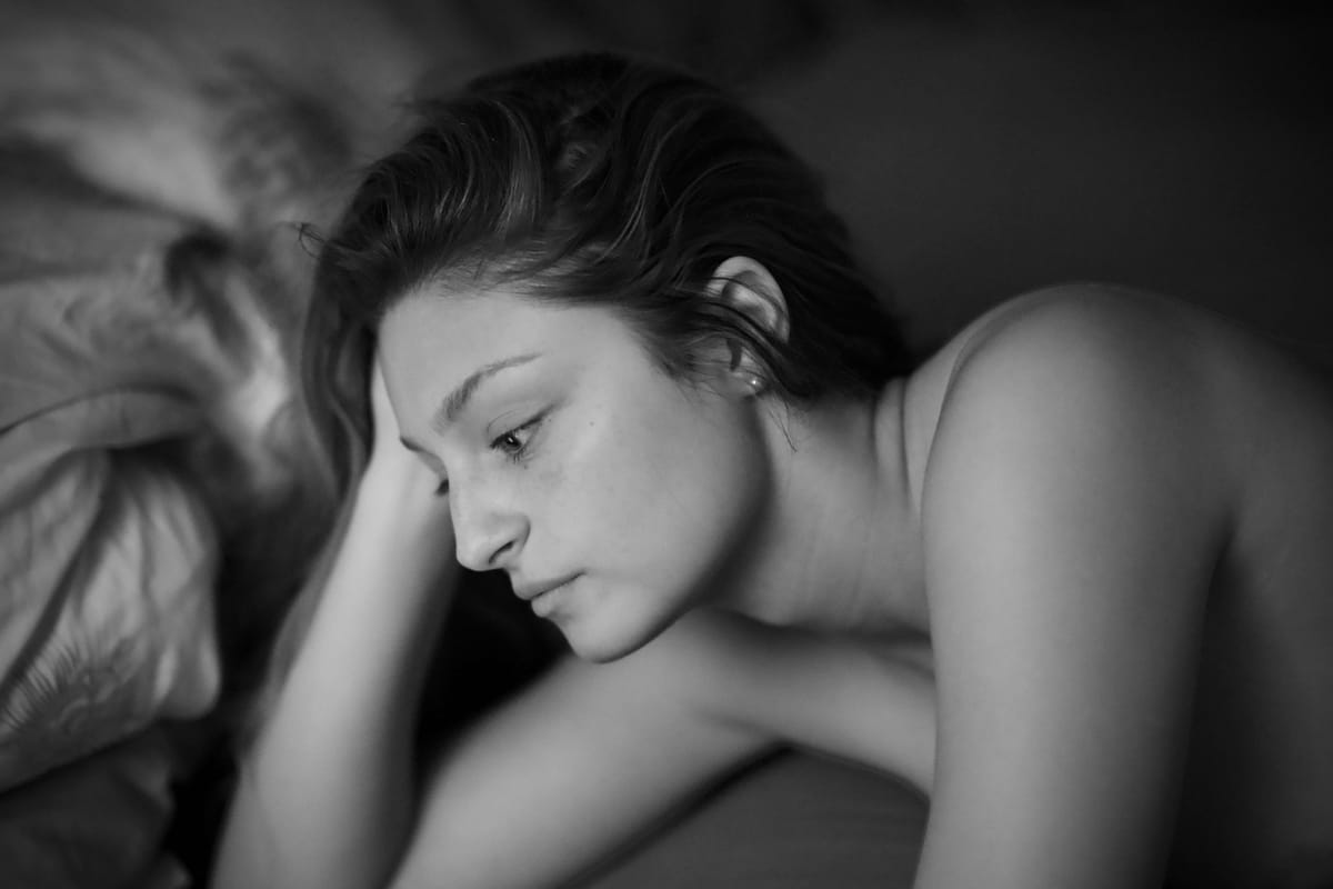 Black and white portrait of a woman in bed emotional